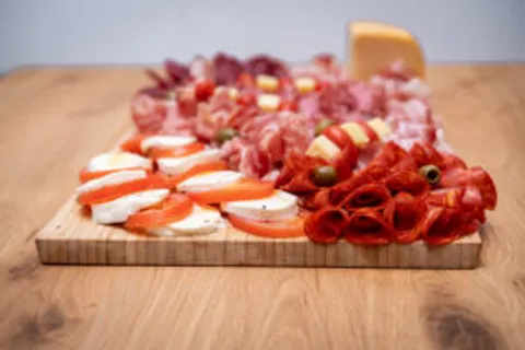 Antipasti-Platte mit Salami, Rohschinken, Mozzarella und Tomaten auf einem Holzbrett