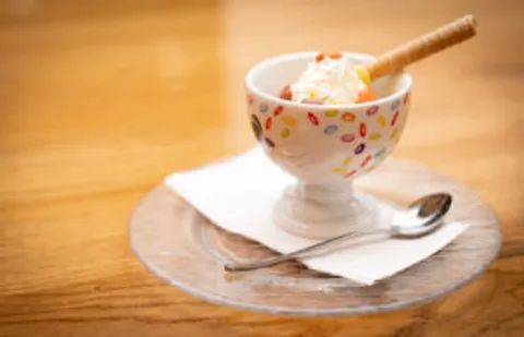 Glace-Dessert mit Waffelröllchen in einer bunt gemusterten Schale